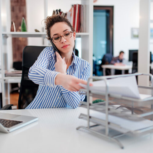 Une assistante juridique au bureau fait de la paperasse et parle au téléphone